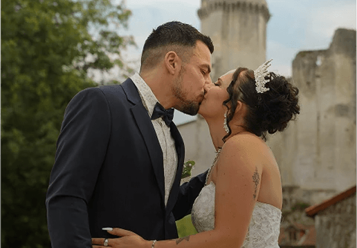 Couple de mariés s’embrassant devant un château en plein air