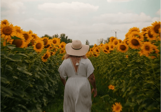 Femme portant un chapeau dans un champ de tournesols en Dordogne
